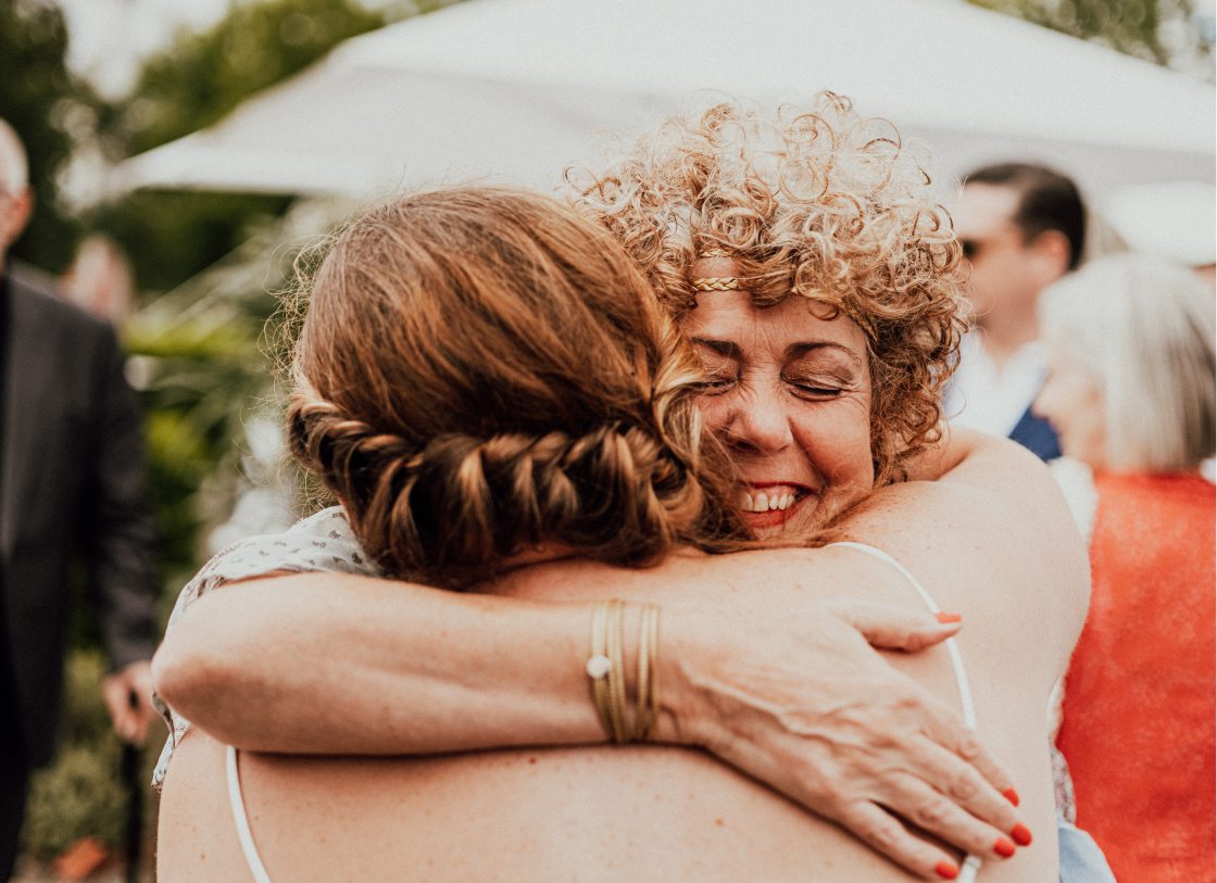 Eine Frau umarmt eine andere Frau bei einer Hochzeit.