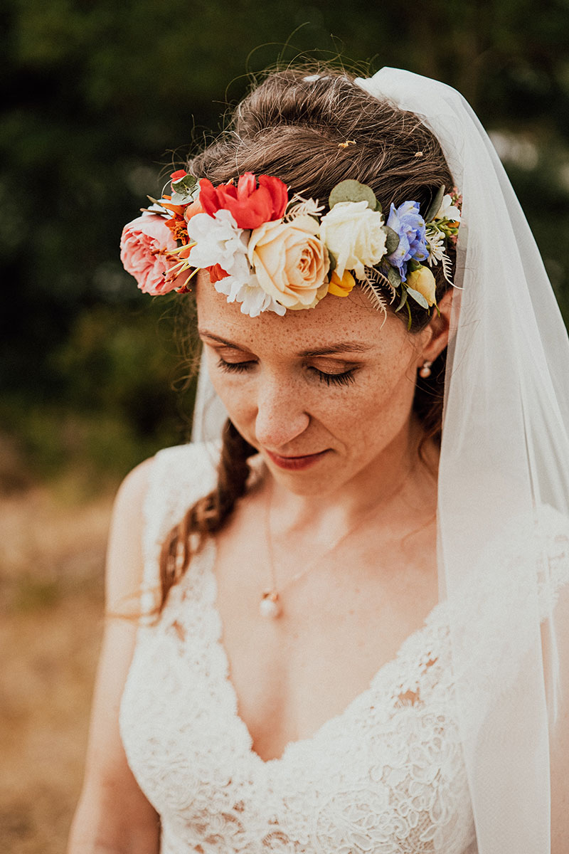 Braut in Spitzenkleid mit Blumen im Haar und geschlossenen Augen